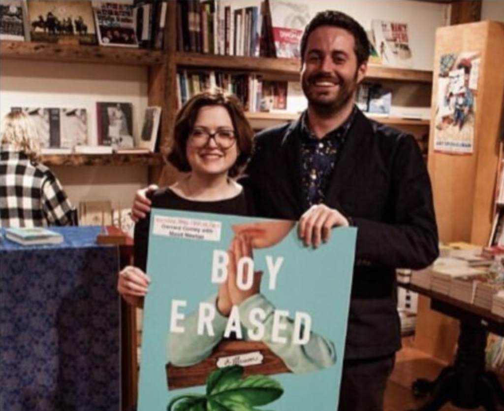 Image shows the authors Maud Newton and Garrard Conley standing behind a poster for Conley's memoir, BOY ERASED.